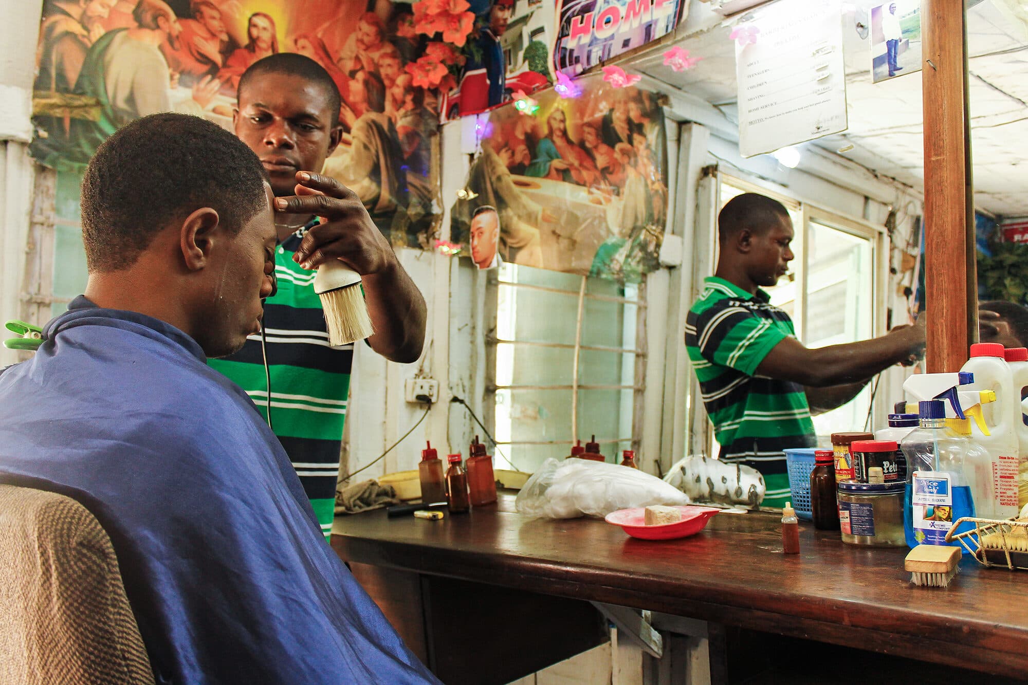 A customer in the chair reflected in a barbershop mirror