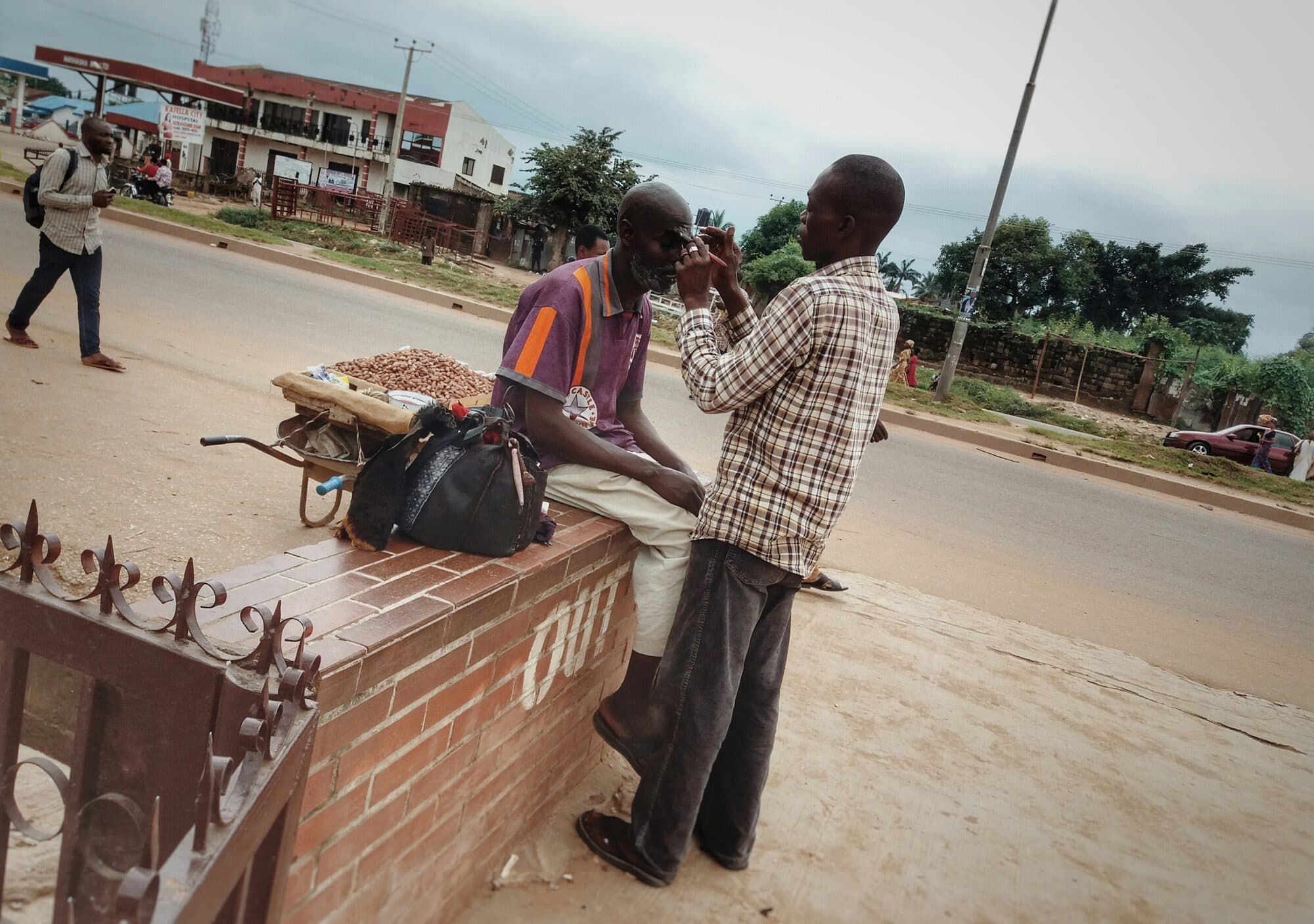 A barber cutting hair at a stand on the roadside