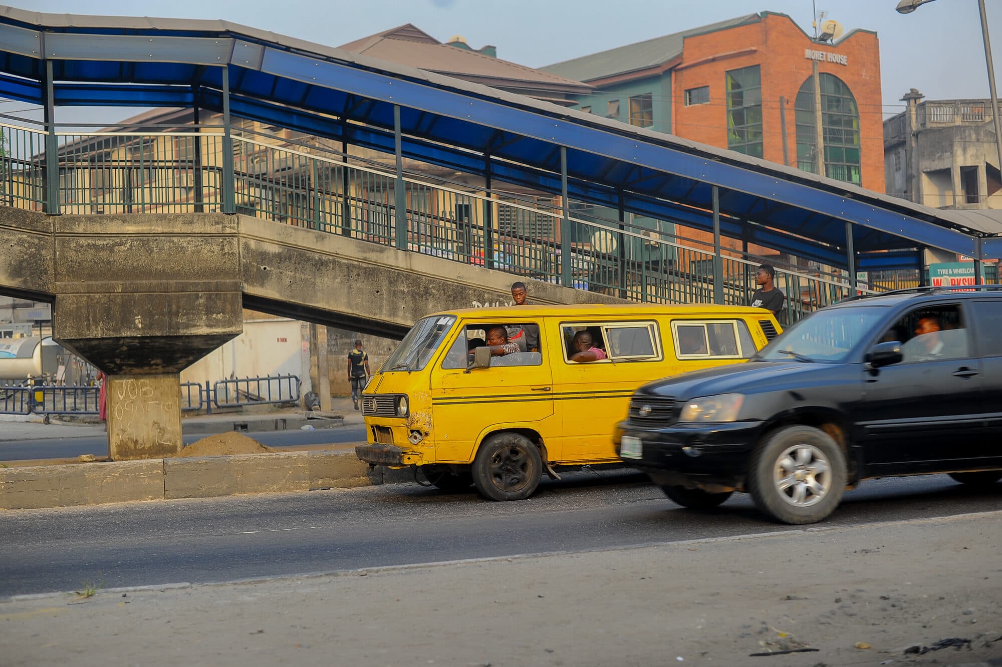 Yellow buses lined along a road under a flyover