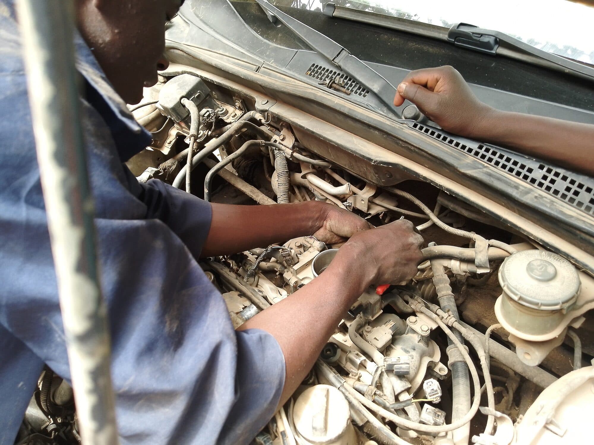 Hands working inside an open engine bay