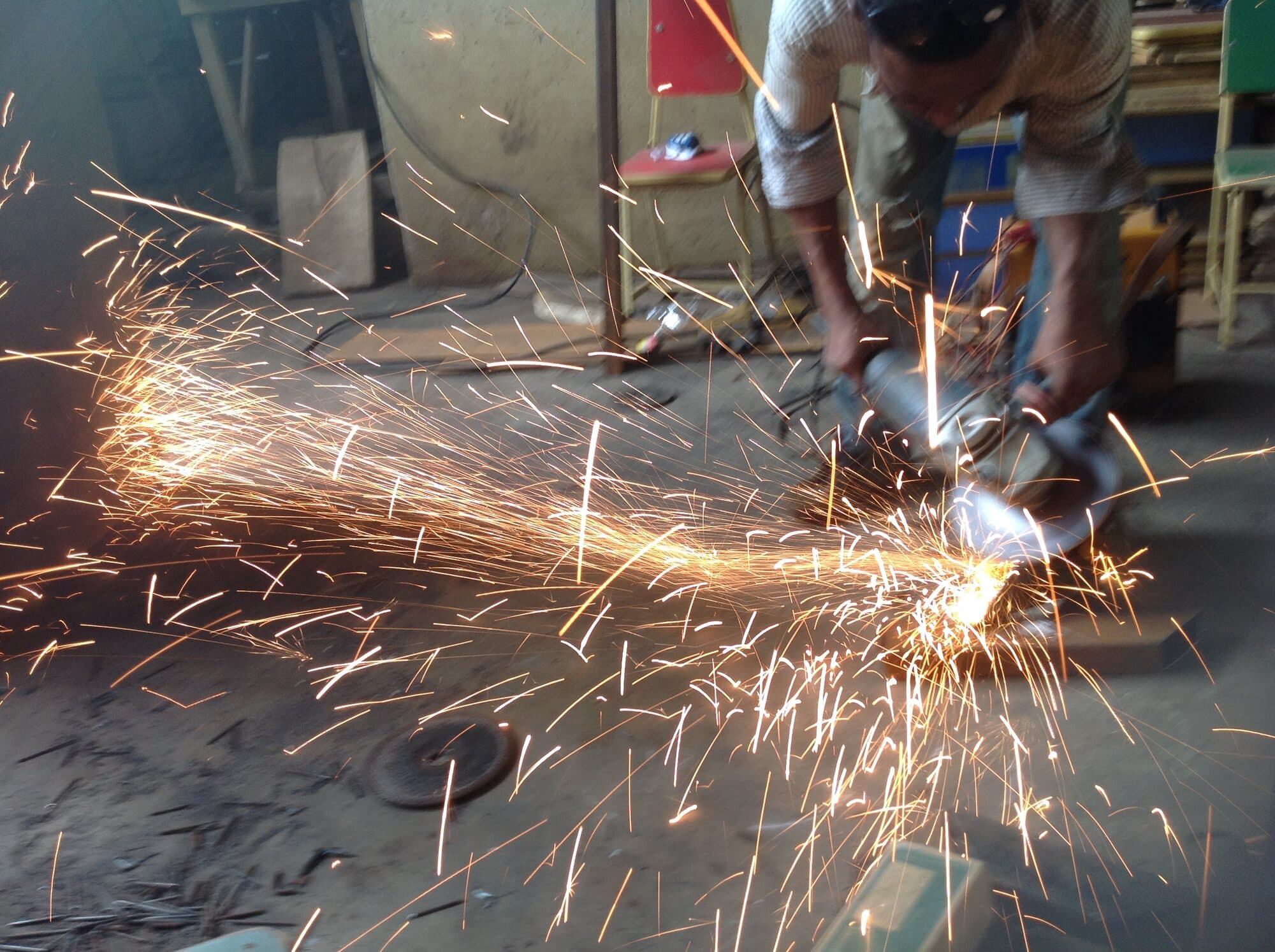 An angle grinder throwing a wide arc of sparks across a yard