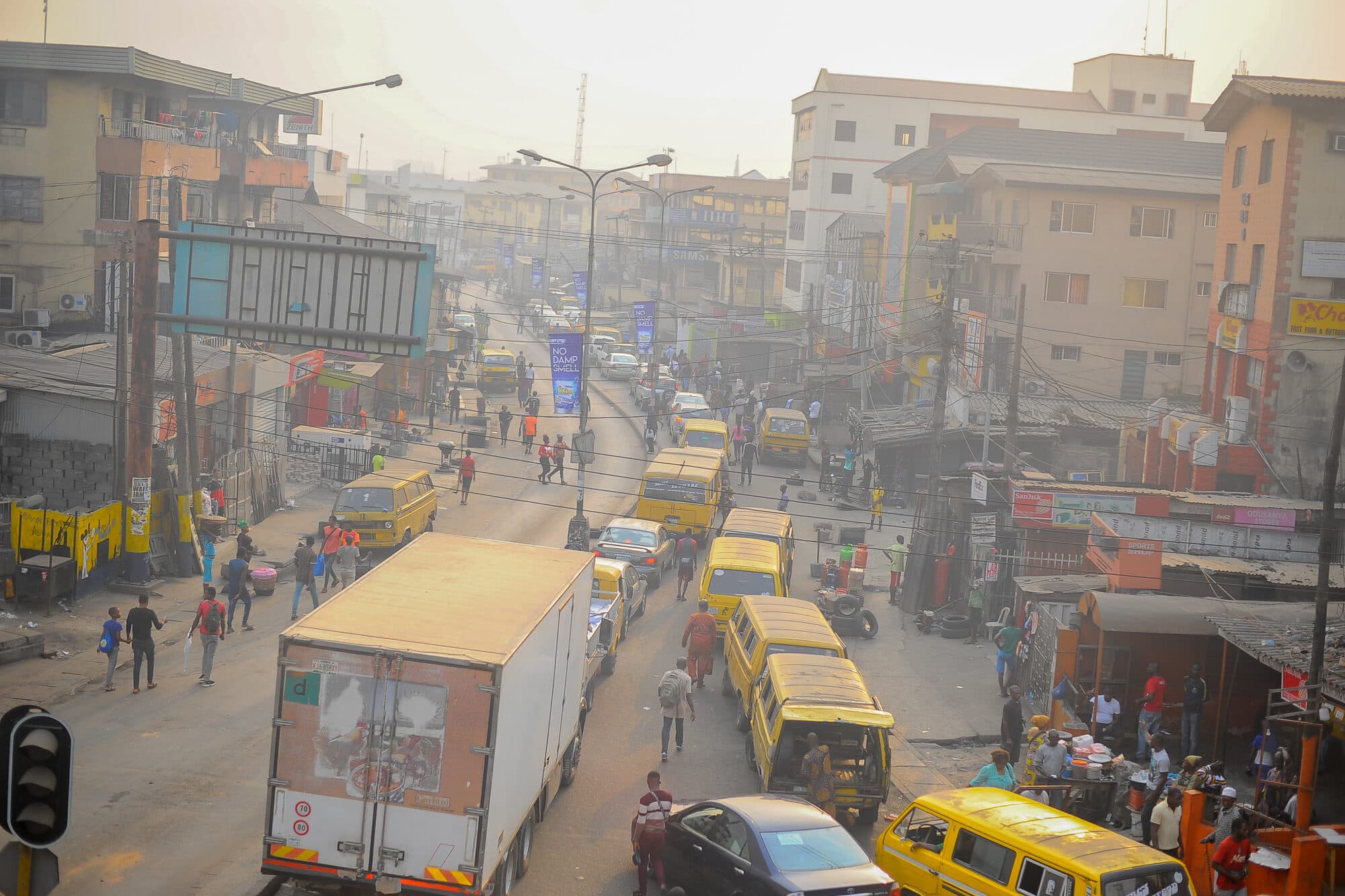 A busy street in afternoon haze, buses and stalls