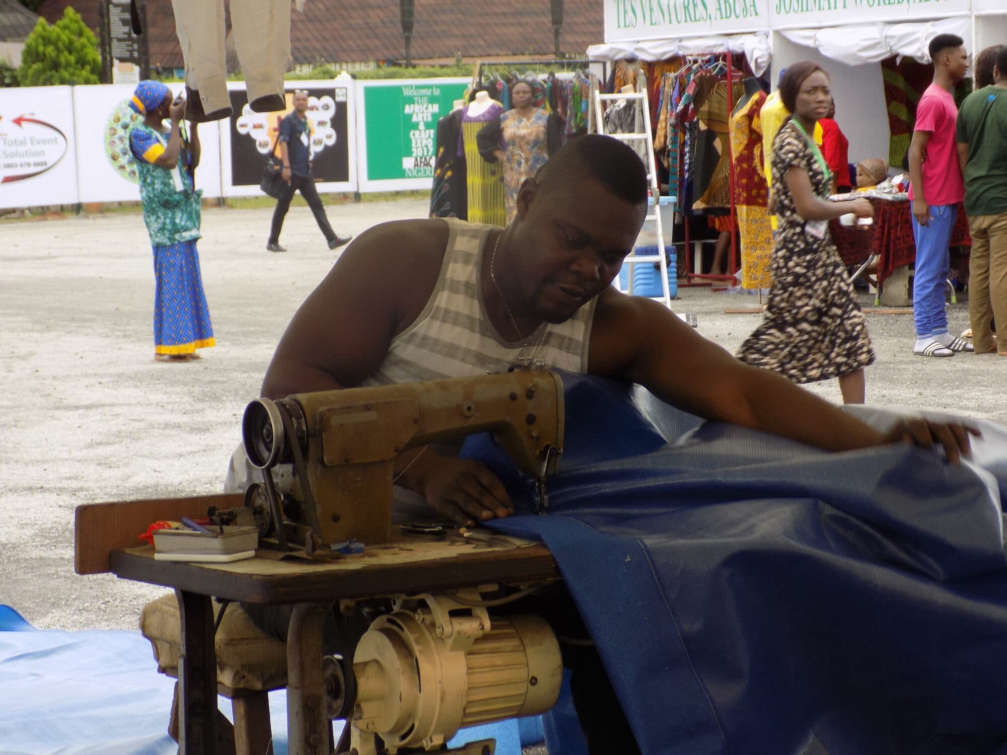 A tailor working a bolt of cloth through a treadle machine