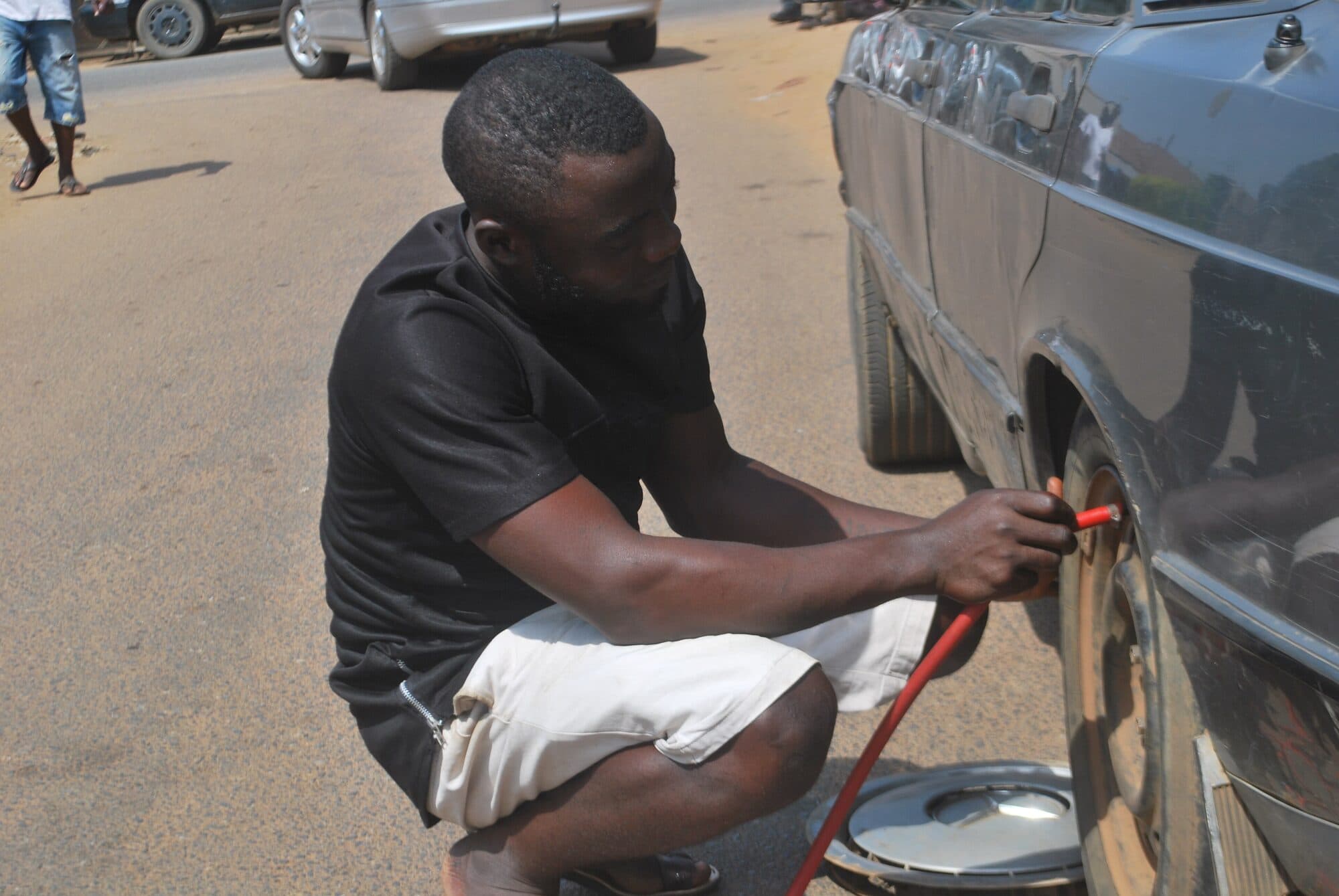 A vulcaniser levering a tyre off its rim at the roadside