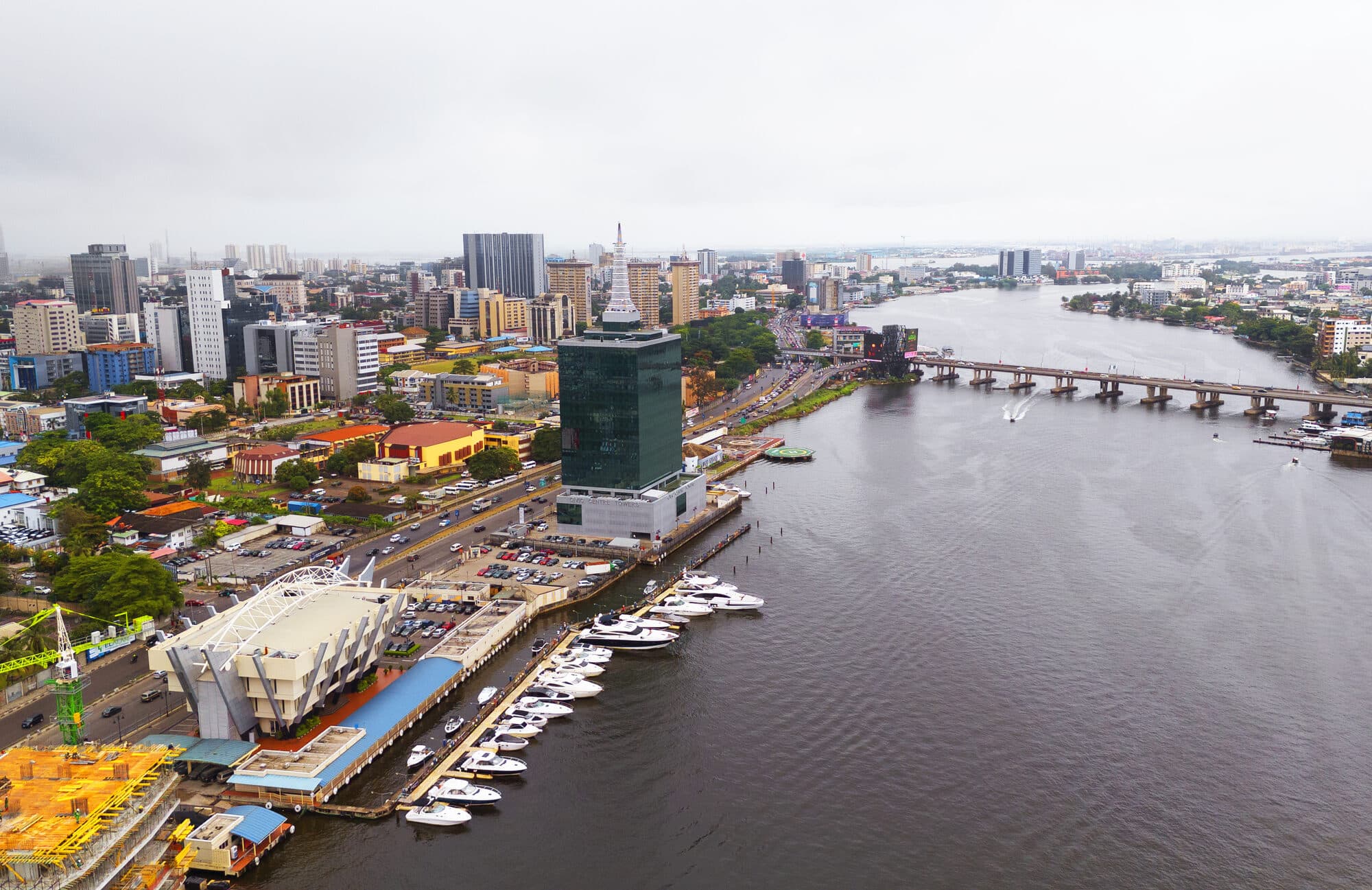 A city waterfront with boats and a bridge beyond