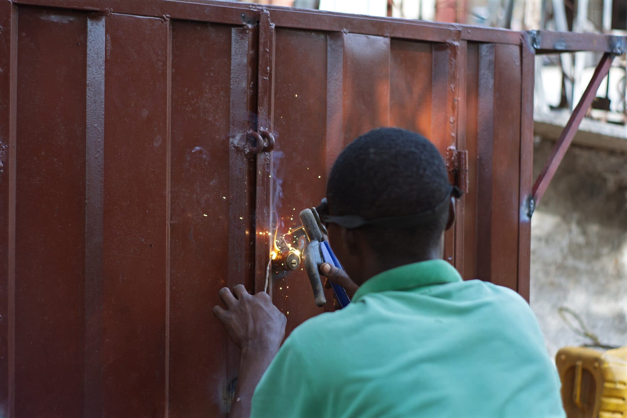 A welder running a seam down a steel gate